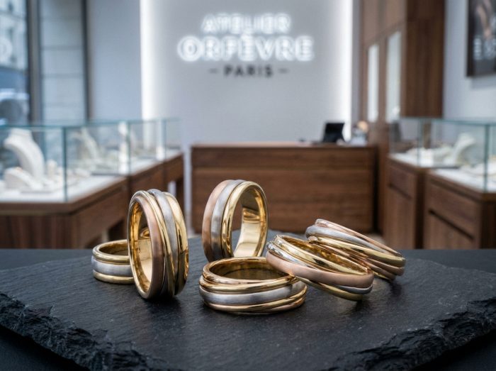 Plusieurs bagues trois ors exposées sur ardoise noire dans une bijouterie de luxe au décor élégant