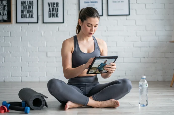 Femme passionnée de sport féminin consultant des articles sportifs sur une tablette dans un espace fitness à domicile